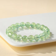 Green beaded bracelet on a white surface with a yellow background