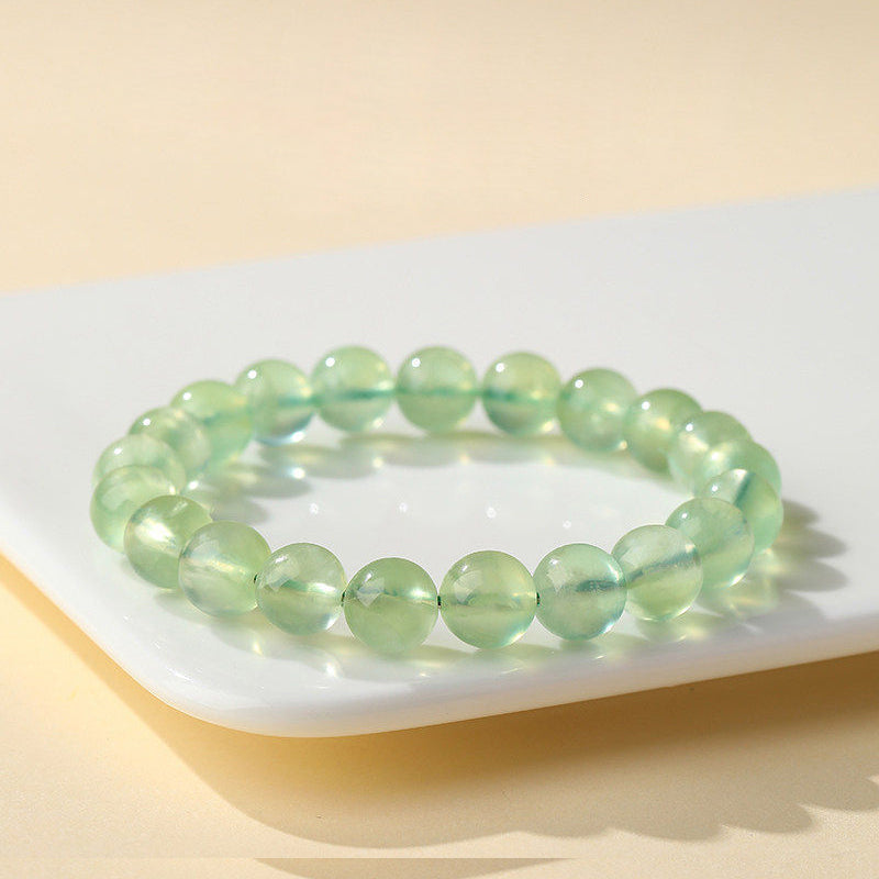 Green beaded bracelet on a white surface with a yellow background
