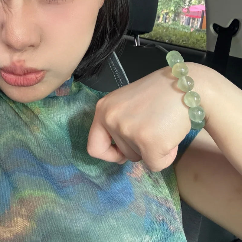 Person wearing a green jade bracelet sitting in a vehicle.