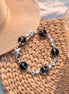 Bracelet with starfish and black bead design on a woven mat with a hat and glass of lemonade.