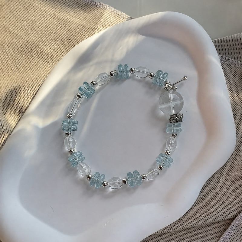 Beaded bracelet with blue and clear beads on a white shell
