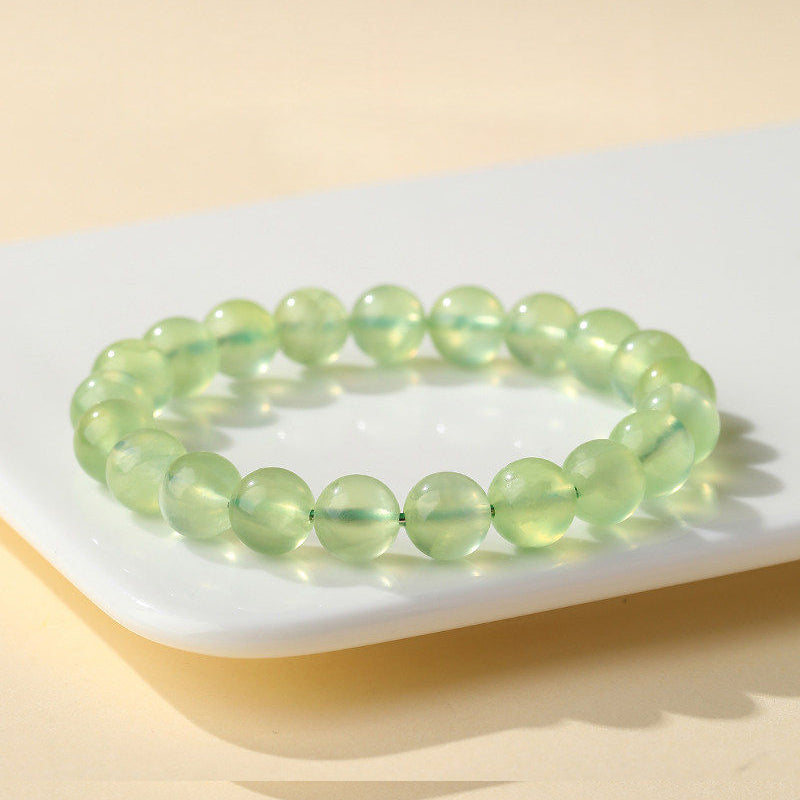 Green beaded bracelet on a white plate with a beige background