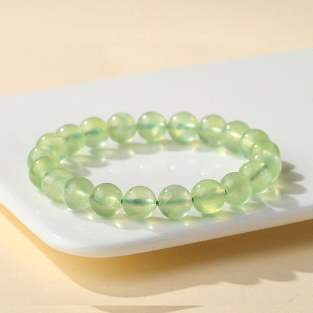 Green beaded bracelet on a white plate with a beige background